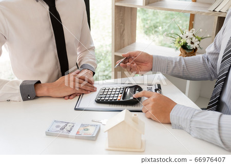 A real estate agent with House model is talking to clients about buying home insurance. Home insurance concept A real estate agent with House model is talking to clients about buying home insurance. Home insurance concept 66976407