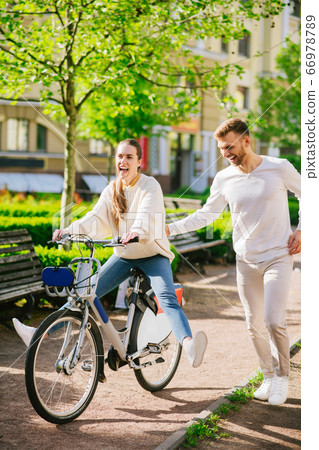 Cheerful woman on bicycle and attentive man running nearby 66978789