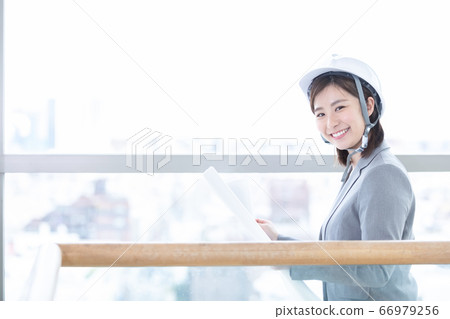 Business woman wearing a helmet and looking at the drawing Business woman wearing a helmet and looking at the drawing 66979256