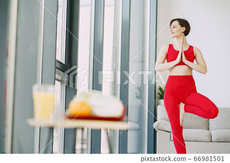 Girl in a red sports uniform make yoga at home 66981501
