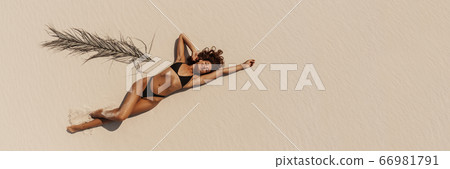Top Aerial Drone View of Woman in Swimsuit Bikini Relaxing and Sunbathing on Beach 66981791