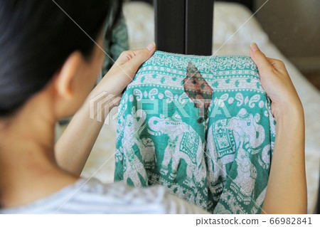 Women hold short pants with period blood spot stains on blur background. Need to be cleaned. 66982841