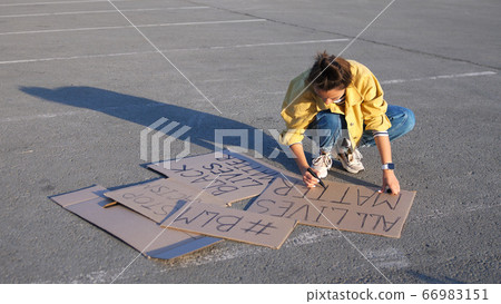 Young woman writing poster with sign all lives matter at an outdoor Young woman writing poster with sign all lives matter at an outdoor 66983151