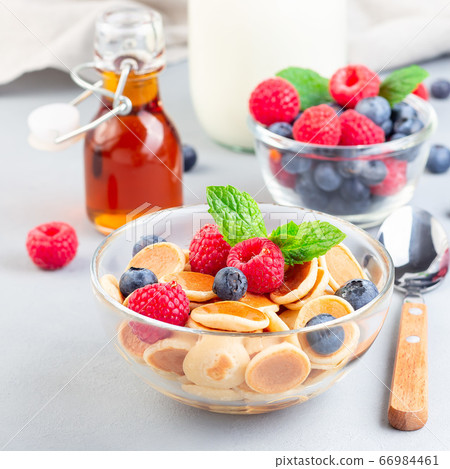 Tiny cereal pancakes served with maple syrup Tiny cereal pancakes served with maple syrup 66984461