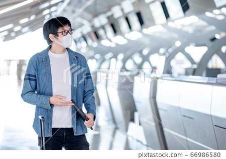 Asian man tourist wearing mask in airport terminal Asian man tourist wearing mask in airport terminal 66986580