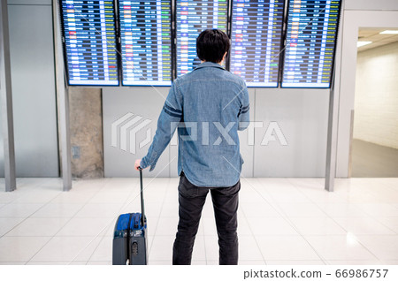 Asian man tourist at arrival departure board in Asian man tourist at arrival departure board in 66986757
