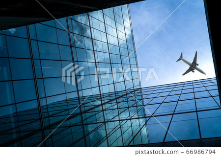 Airplane flying above glass office building. Airplane flying above glass office building. 66986794