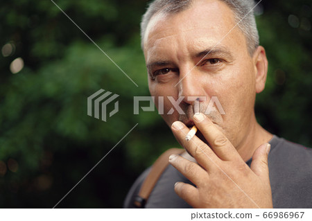 Caucasian mature middle aged man smoking cigarette outdoors. Nicotine addiction. Copy space 66986967