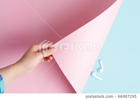 Woman hand is turning pastel pink colored paper 66987295