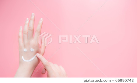 Beautiful woman hands applying moisturizing cream on pink background. Smiling emoji shape created from lotion. Take care of your body skin. Health care and beauty concept. Top view. Beautiful woman hands applying moisturizing cream on pink background. Smiling emoji shape created from lotion. Take care of your body skin. Health care and beauty concept. Top view. 66990748