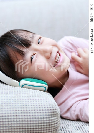躺在沙發上聽音樂的耳機上的女孩 66991108