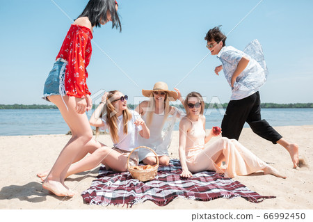 Seasonal feast at beach resort. Group of friends celebrating, resting, having fun on the beach in sunny summer day 66992450