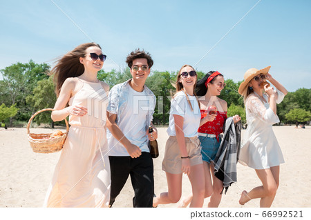 Seasonal feast at beach resort. Group of friends celebrating, resting, having fun on the beach in sunny summer day Seasonal feast at beach resort. Group of friends celebrating, resting, having fun on the beach in sunny summer day 66992521