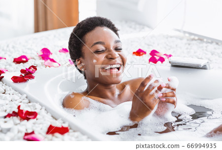 Rest staying at home. Laughing african american girl in bathroom with foam and petals Rest staying at home. Laughing african american girl in bathroom with foam and petals 66994935