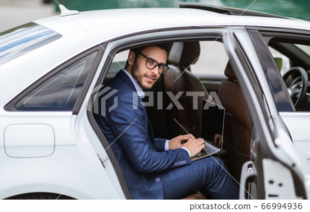 Handsome businessman working with laptop computer sitting at back seat of car, empty space for design on screen 66994936