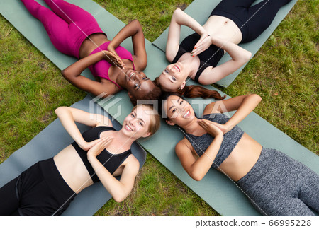 Top view of diverse women lying on yoga mats and making namaste gesture outdoor 66995228