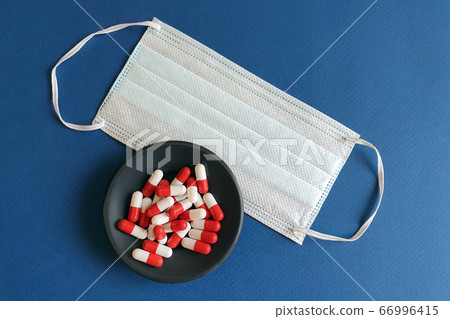 medicines and protective masks. Novel coronavirus 2019-nCoV, MERS-Cov middle. Medical pills on a black plate and medical mask. Blue background. Cure for the coronavirus and End of coronavirus concept. 66996415