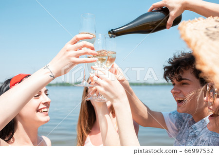Seasonal feast at beach resort. Group of friends celebrating, resting, having fun on the beach in sunny summer day 66997532