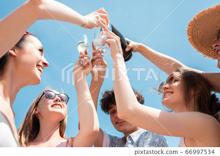 Seasonal feast at beach resort. Group of friends celebrating, resting, having fun on the beach in sunny summer day 66997534