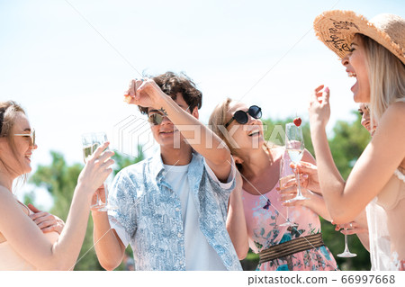 Seasonal feast at beach resort. Group of friends celebrating, resting, having fun on the beach in sunny summer day 66997668