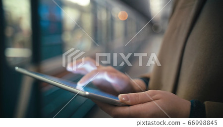 Woman using tablet PC by the leaving train in subway 66998845