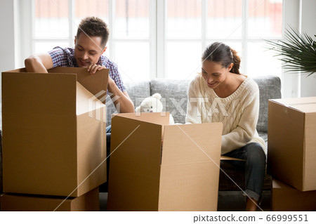 Young couple packing or unpacking boxes together, moving day con 66999551