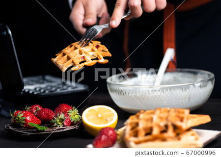 Man making waffles on a waffle machine Man making waffles on a waffle machine 67000996