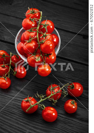Cherry tomato branch, fresh ripe organic vegetables on dark black textured background, macro angle view 67002852