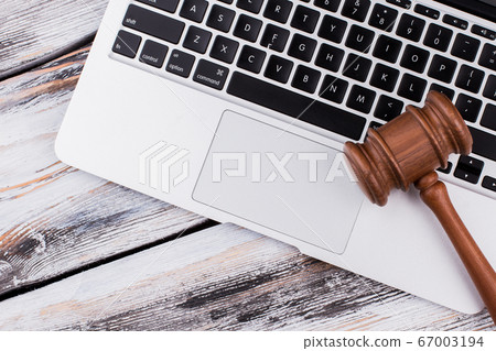 Wooden court gavel on a laptop keyboard. Wooden court gavel on a laptop keyboard. 67003194