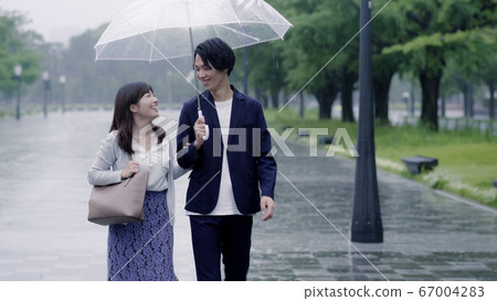 Couple dating with an umbrella on a rainy day Couple dating with an umbrella on a rainy day 67004283