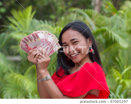 Indonesian money in the hands of an asian girl. 67005297