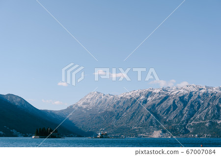 The island of St. George and the Island of Gospa od Skrpela in Kotor Bay, near Perast, Montenegro, against the backdrop of snow-capped mountains in winter. The island of St. George and the Island of Gospa od Skrpela in Kotor Bay, near Perast, Montenegro, against the backdrop of snow-capped mountains in winter. 67007084