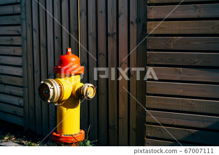 Yellow fire hydrant with red cap and silver lids, On a wooden background. Yellow fire hydrant with red cap and silver lids, On a wooden background. 67007111
