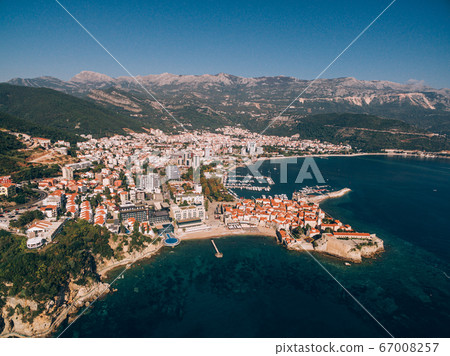Aerial photo from the drone - a view from the sea on the old town of Budva, Richard's beach head and a modern city against the backdrop of the mountains. Aerial photo from the drone - a view from the sea on the old town of Budva, Richard's beach head and a modern city against the backdrop of the mountains. 67008257