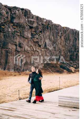 A guy and a girl are walking down the road in the Silfra Fault, in the Tingvedlir Valley. 67008325