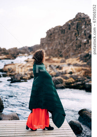 A girl in a red dress near Ehsaraurfoss Falls, Ehsarau River, National Park, Tingwedlir, Sudurland region. A girl in a red dress near Ehsaraurfoss Falls, Ehsarau River, National Park, Tingwedlir, Sudurland region. 67008352