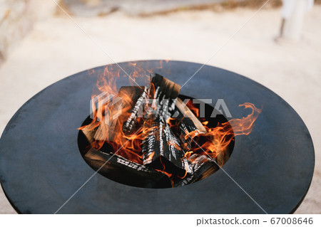A close-up of the round frying surface with burning wood inside.  67008646