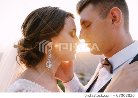 Fine-art wedding photo in Montenegro, Perast. Close-up portrait of a wedding couple, the groom strokes the bride on the cheek with his hand at sunset. 67008826
