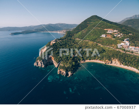 Mogren Beach, near the old town of Budva, in Montenegro. The ancient Mogren Fort on the mountain. Rocky cliffs on the Adriatic coast. 67008937