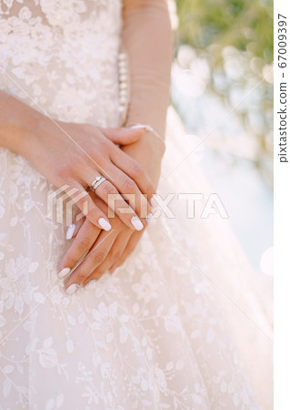 Close-up of the bride's hands with a wedding ring on a cream dress background. Fine-art wedding photo in Montenegro, Perast. 67009397
