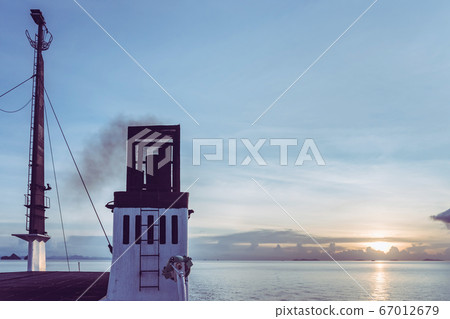 Exhaust pipe of ferry boat with black thick smoke coming out and sky with clouds on background. Air pollution. 67012679