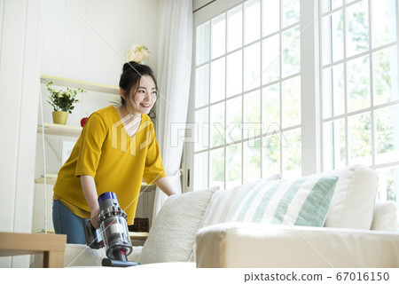 Young woman cleaning the sofa 67016150