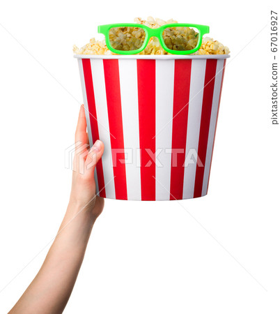 Woman hand holding striped bucket with popcorn and Woman hand holding striped bucket with popcorn and 67016927