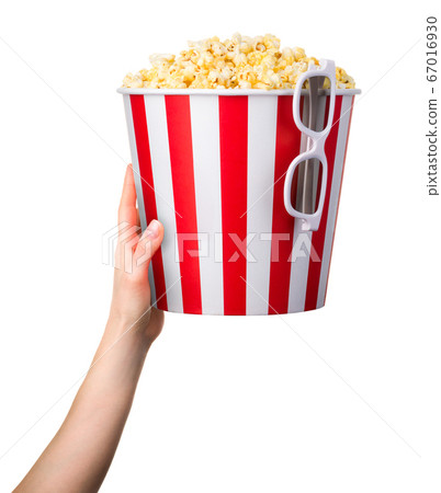 Woman hand holding striped bucket with popcorn and Woman hand holding striped bucket with popcorn and 67016930