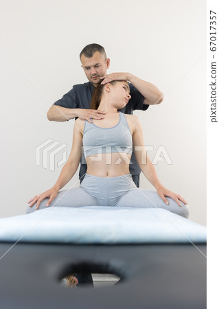 Chiropractic treatment - young woman sitting on the couch - the doctor turning her head to the side 67017357