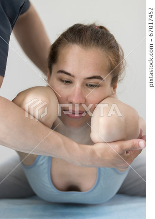 Young woman having osteopathy treatment indoors - lying in the pose with her elbows forward Young woman having osteopathy treatment indoors - lying in the pose with her elbows forward 67017452