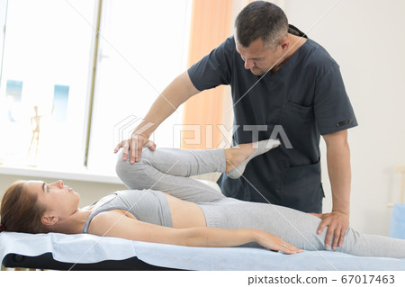 Young woman having osteopathy treatment - pushing on the leg Young woman having osteopathy treatment - pushing on the leg 67017463