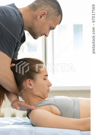 Osteopath treatment - the master holding the neck and leans on shoulders of young woman Osteopath treatment - the master holding the neck and leans on shoulders of young woman 67017569