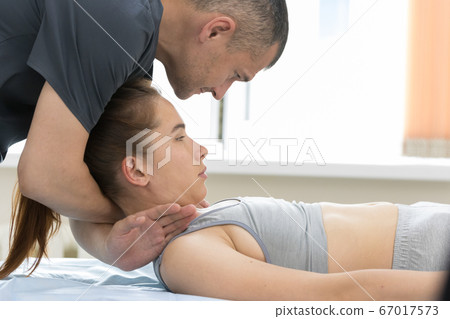 Osteopath treatment - the medical master holding the neck of young woman Osteopath treatment - the medical master holding the neck of young woman 67017573