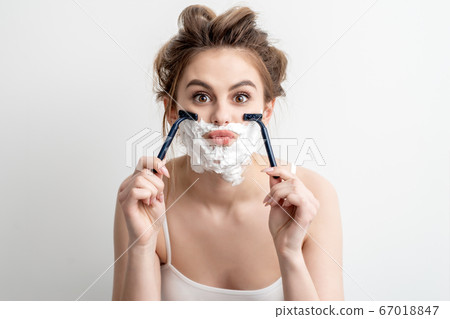 Woman with shaving foam on her face 67018847